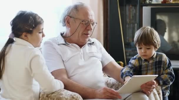 Yaşlı bir adam bir tablet bilgisayar torunları ile kullanma — Stok video