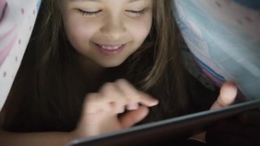 Küçük kız on yıl dijital tablet örtü altında geceleri kullanır