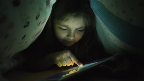 Uma menina de dez anos usa um tablet à noite — Vídeo de Stock