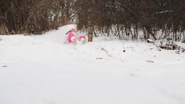 Девочка спускается с зимней горки — стоковое видео