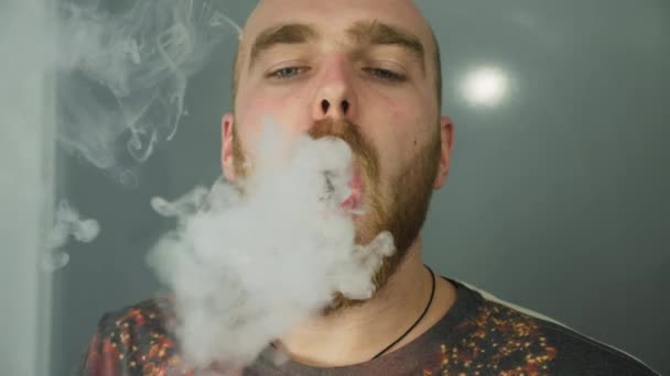 Молодой человек с бородой испачкал электронную сигарету — стоковое видео