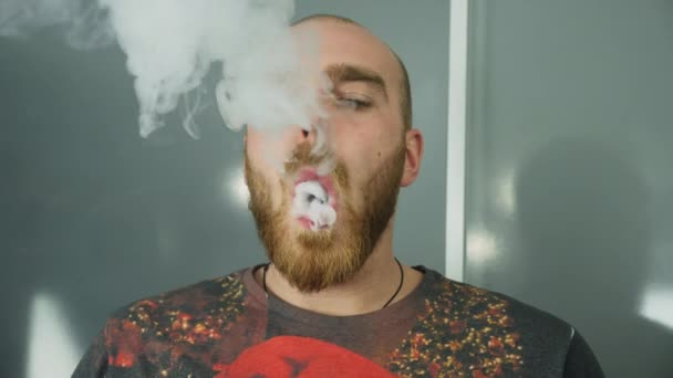Молодой человек с бородой испачкал электронную сигарету — стоковое видео