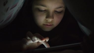 Gece bir battaniyenin altında bir tablet ile oynamak