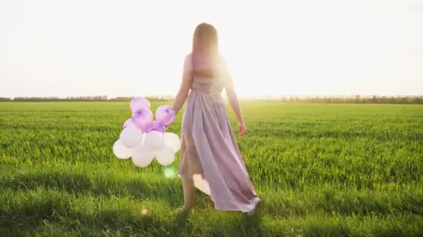 Szépség lány séta a tavaszi mezőt színes levegő léggömbök — Stock videók