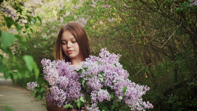 Genç esmer kadın leylak kokusunu tadını çıkartıyor