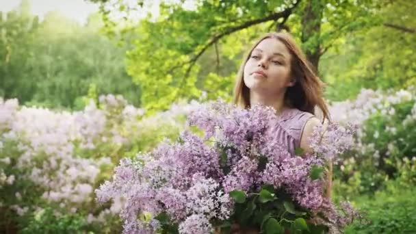 La joven está disfrutando del aroma de la lila — Vídeo de stock