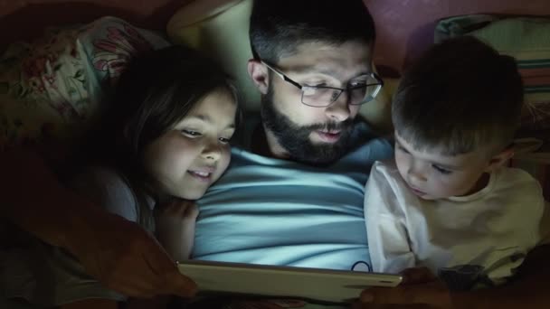 Padre con niños pequeños surfeando en la tableta antes de dormir — Vídeos de Stock