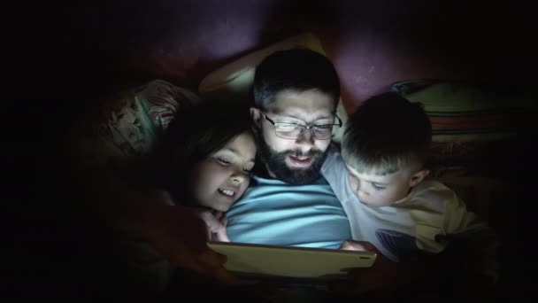 Vater mit kleinen Kindern surft vor dem Schlafen auf Tablet-Computer — Stockvideo
