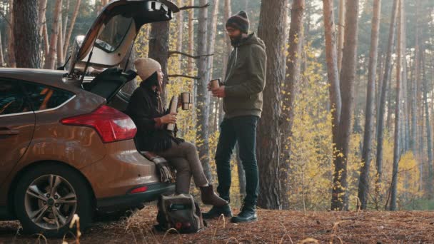 Пара пьет кофе возле машины в лесу — стоковое видео