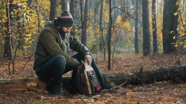 Бородатий хлопець з рюкзаком в осінньому лісі — стокове відео