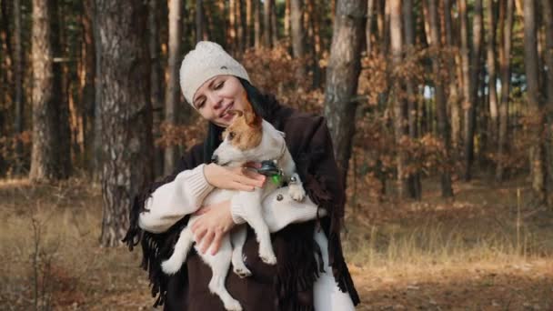 Boldog nő tartja és simogatja a kutyát az erdőben — Stock videók