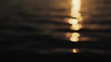 Güneş, kehribar günbatımında dalgaların üzerinde parlıyor.