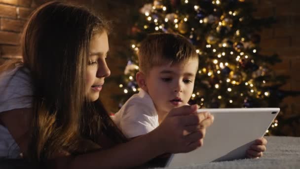 Sister with little brother use a digital tablet — Stock Video