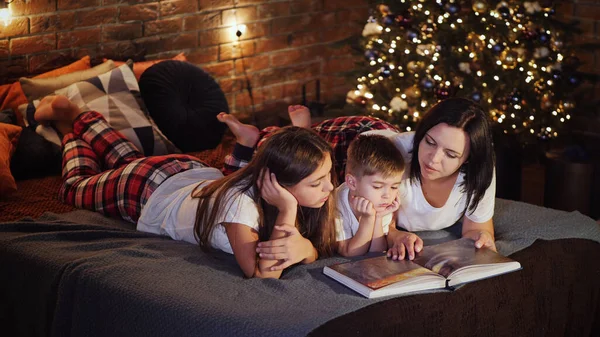 Mom reads a book to children in the bedroom