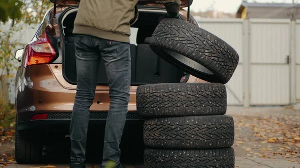 Um homem coloca pneus de inverno no porta-malas de um carro Imagem De Stock