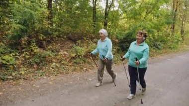 Yaşlı yaşlı kadınlar dışarıda İskandinav yürüyüşü yapıyorlar.