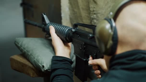 Un homme tire avec une carabine automatique dans une galerie de tir — Video