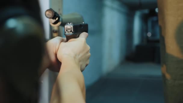 Menina faz pontaria segurando uma arma em suas mãos — Vídeo de Stock