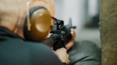 Bir adam atış poligonunda otomatik tüfekle ateş eder.