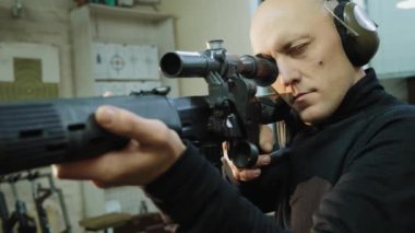 Bir adam keskin nişancı tüfeğinin optik görüntüsüne bakar.