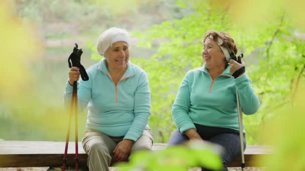 Twee oudere dames lachen, praten, ontspannen na een nordic walk — Stockvideo