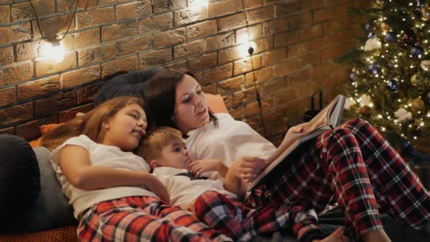 Mutter liest Kindern im Schlafzimmer ein Buch vor — Stockvideo