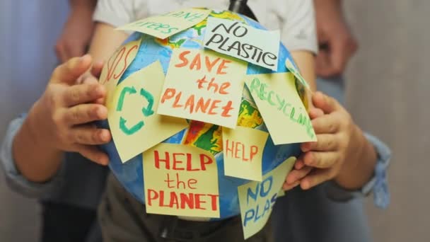 Семейные Руки Обнимают Земной Шар Наклейками Сообщением Planet Help Plastic — стоковое видео