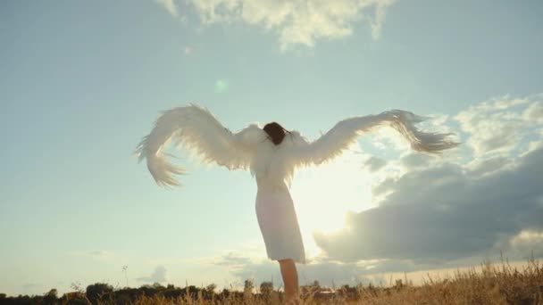 Žena v bílých šatech zvedá andělská křídla