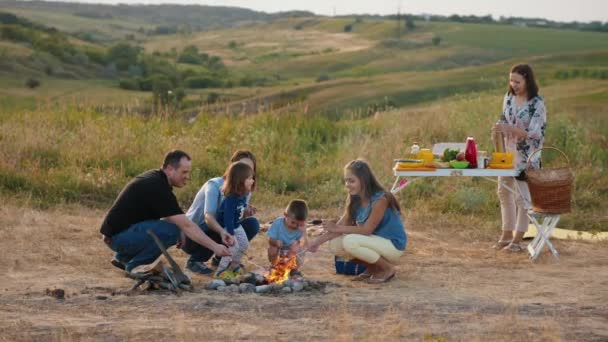 Lycklig familj med barn runt lägerelden på picknick — Stockvideo