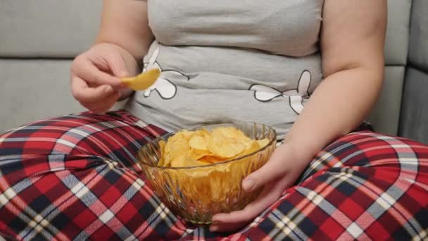 Толстушка ест чипсы из миски — стоковое видео