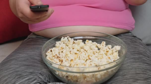 Fat woman sit and eat popcorn on the sofa — Stock Video
