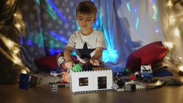 Menino brinca com construtor de plástico em casa — Vídeo de Stock