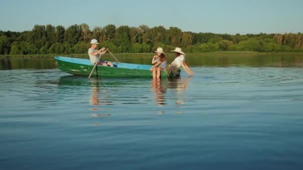 Молодая семья плавает в зеленой деревянной лодке — стоковое видео