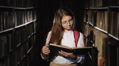 Girl with glasses reading a book in the library