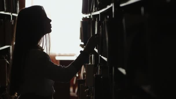A female student searching for a book — Stockvideo