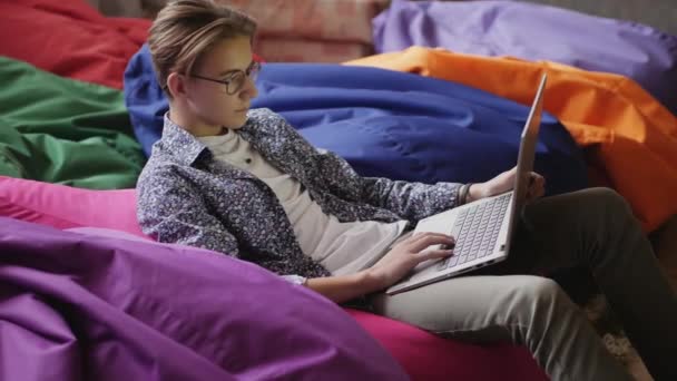 Um adolescente com óculos usando um laptop — Vídeo de Stock