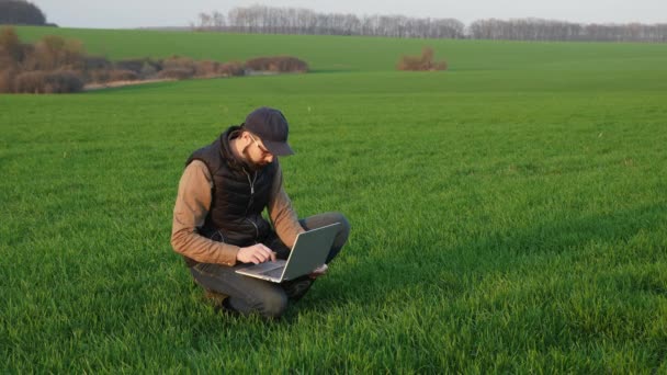Человек фермер, работающий на ноутбуке в поле — стоковое видео