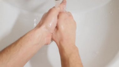 Adam ellerini banyoda sıvı sabunla yıkıyor.