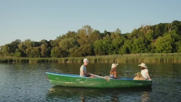 Люди пливуть у зеленому дерев'яному човні — стокове відео