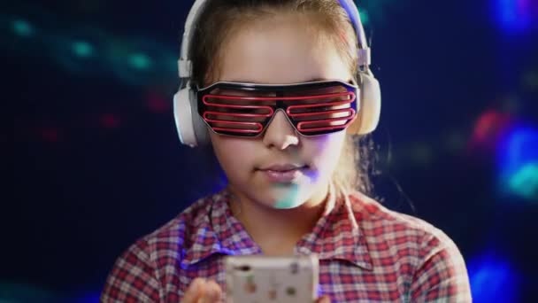 Εφηβική κοπέλα χρησιμοποιεί ένα smartphone, ακούγοντας μουσική στα ακουστικά — Αρχείο Βίντεο