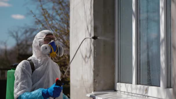 Worker in protective suit sprays a disinfectant on the window — Stock Video