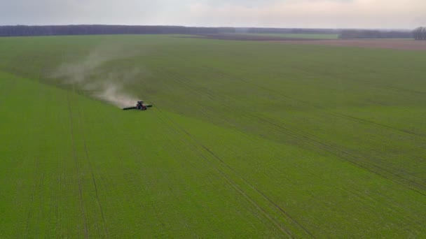 En traktor arbetar på ett grönt fält. Flygbild — Stockvideo