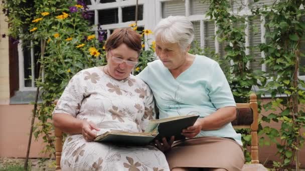 Ηλικιωμένες γυναίκες κοιτάζουν παλιές φωτογραφίες σε ένα άλμπουμ — Αρχείο Βίντεο