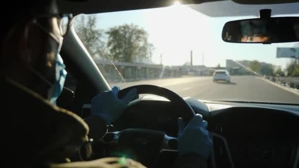 A sofőr orvosi maszkban és kesztyűben autót vezet. — Stock videók