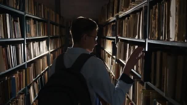 Um estudante do sexo masculino procurando um livro — Vídeo de Stock