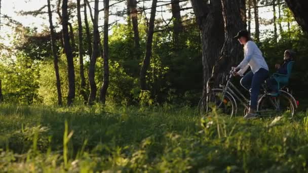 Moeder met haar zoontje fietsen door bos — Stockvideo