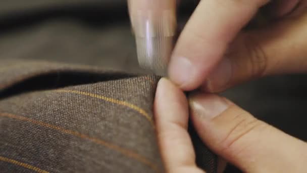 Cucire un bottone su una giacca marrone abito su misura, primo piano — Video Stock