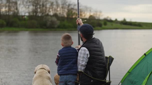 Ayah dengan anak laki-laki dan anjing memancing, pandangan belakang — Stok Video