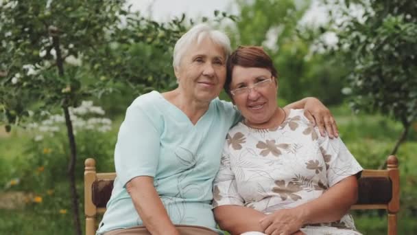Две пожилые женщины улыбаются, глядя в камеру . — стоковое видео