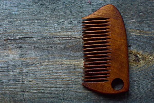 Comb for a beard lies on a wooden background.